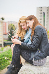 Two young girls using technological devices