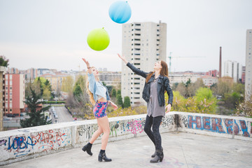Two beautiful blonde and brunette girls playing with baloons