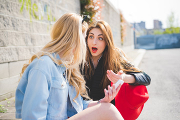 Fototapeta premium Two young blonde and brunette girls chatting