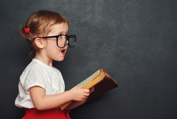 funny happy  girl schoolgirl with book from blackboard