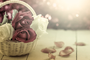 beautiful roses in basket on wooden background  in vintage color