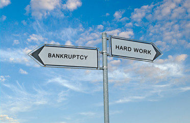 Fototapeta premium Road sign to bankruptcy and hard work