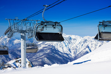 Fototapeta na wymiar Chairs on chairlift ropeway in winter mountains