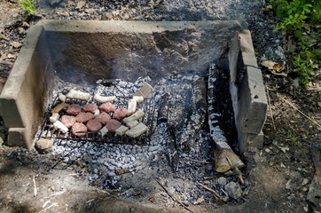 Steaks cooking over hot coals from open fire