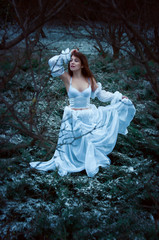 Fototapeta premium Woman in white dress lost in winter forest