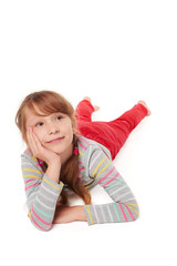 Front view of smiling child girl lying on stomach on the floor with head in hands looking away at blank copy space, over white background