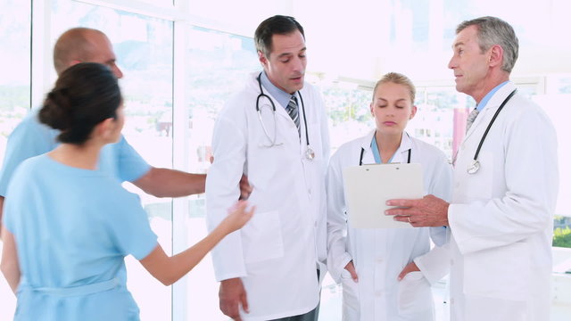 Doctors looking at clipboard and one of them going with surgeon 
