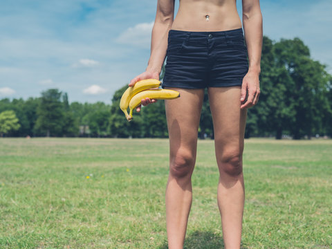 Woman holding two bananas in park