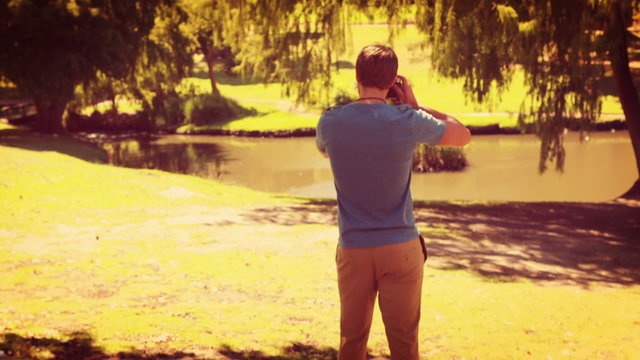 Rear view of man walking and taking photo with retro camera