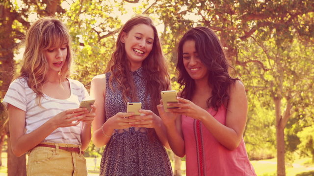Happy female friends using their smartphones and laughing