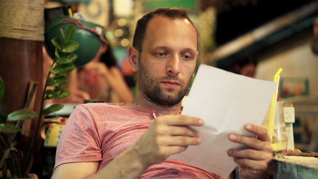 Sad, unhappy man reading bill while sitting in cafe
