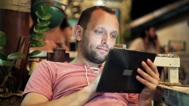 Young man with tablet computer sitting in cafe
