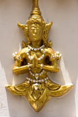 Golden Deva (deity) clasping hands in token of worship. The sculpture is respectfully engaged on walls at places of religious importance, such as temples.