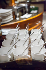 rows of pure white cup and saucer with teaspoon, reflection on t