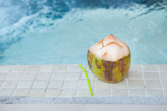 Coconut with straws to drink on the side of the pool