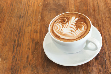 Hot cafe latte with art on top on wood table