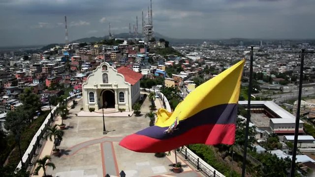 Ecuadorian flag waving in front of a church with Guayaquil in the background in Ecuador