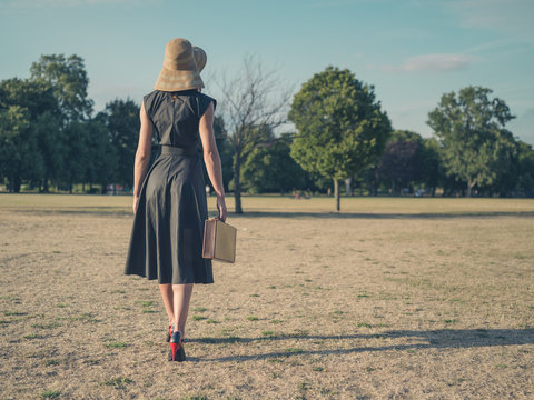 Elegant woman walking in park with briefcase