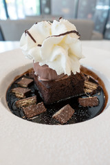 Chocolate fudge cake and ice cream on chocolate sauce and wafer with whip cream on top