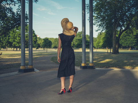 Young woman wearing hat at bandstand in park