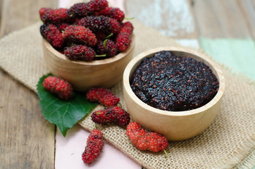 home made mulberry jam in wooden bowl and some fresh fruits and