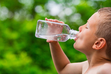 Boy drinking clean tap water from transparent plastic bottle - obrazy, fototapety, plakaty