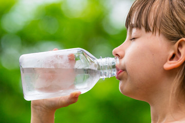 Girl drinking clean tap water from transparent glass bottle - obrazy, fototapety, plakaty