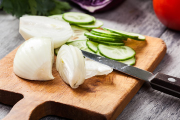 Chopped vegetables: onion and cucumber on cutting board
