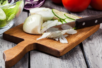 Chopped vegetables: onion and cucumber on cutting board