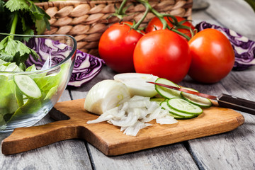 Chopped vegetables: onion and cucumber on cutting board