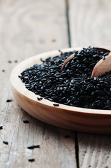 Black uncooked rice on the wooden table