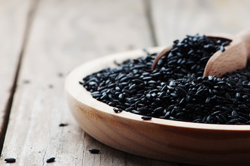 Black uncooked rice on the wooden table
