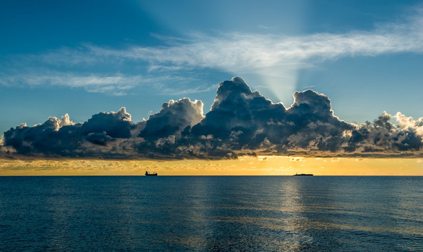 The sun comes out behind the clouds. Sunrise on the coast of Florida. Ship raid. Storm clouds.