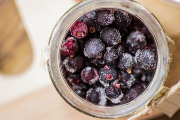 Frozen black currants in a glass jar top view