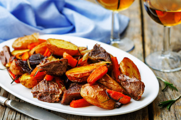 Meat roasted with potatoes, carrots, onions, rosemary and garlic