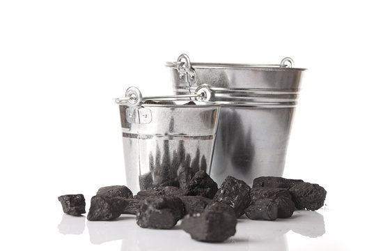 Two empty silver buckets with some loose lumps of black coal on a glossy table