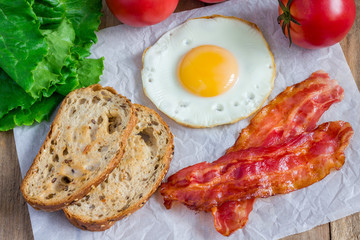 Making open face sandwich with egg, bacon, tomato and lettuce