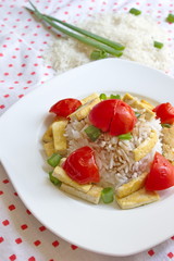 rice with vegetable and pieces of tofu served on stippled tablecloth