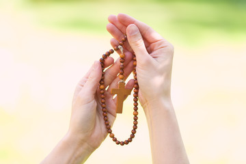 Hands holding wooden rosary 