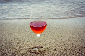 Glass of red wine in the sand