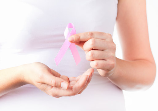  woman`s hands holding pink breast cancer awareness ribbon
