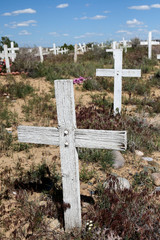 White simple wooden crosses at an overgrown graveyard in NM