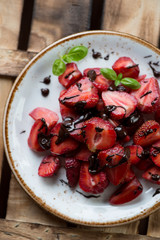 Strawberries with chocolate on a plate, rustic wooden surface
