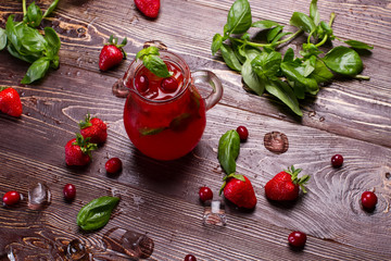 Glass jug of freshness lemonade with strawberries.