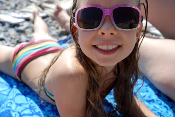 Little girl smiling and liying on the beach
