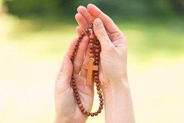 Hand holding wooden rosary beads in close up
