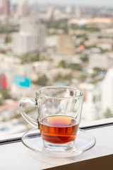 a glass with tea at the window with soft blur city view in background