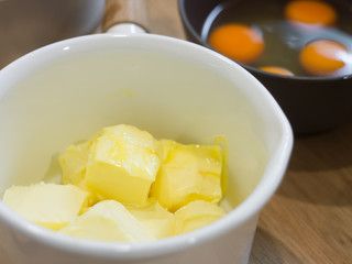 Butter in whte pot and yolk egg on wooden table