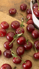 Cherries on wooden chopping board and in white bowl.