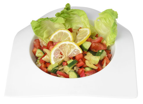Vegetable salad with cucumber, tomatoes, lemon, pepper and salad leaves, isolated on a white background.